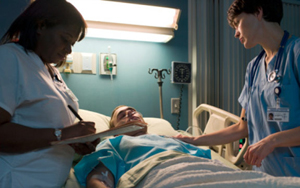 A patient in a coma flanked by nurses